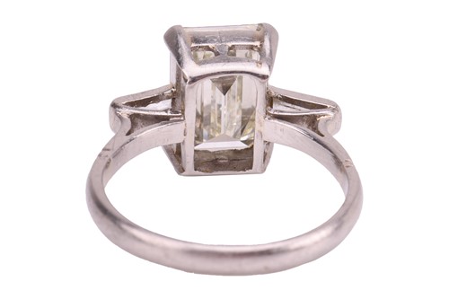 Lot 231 - An emerald-cut diamond trilogy ring, with an...