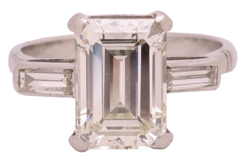 Lot 231 - An emerald-cut diamond trilogy ring, with an...