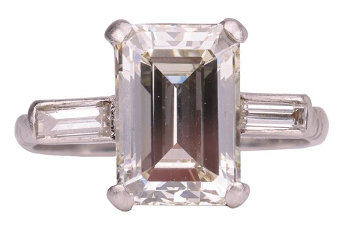 Lot 231 - An emerald-cut diamond trilogy ring, with an...