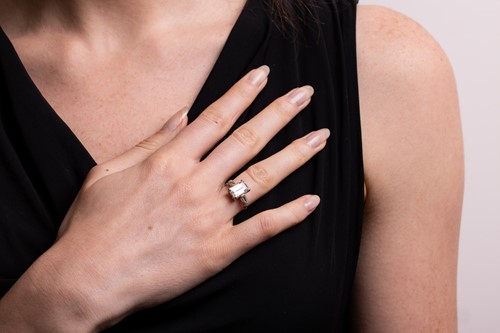 Lot 231 - An emerald-cut diamond trilogy ring, with an...