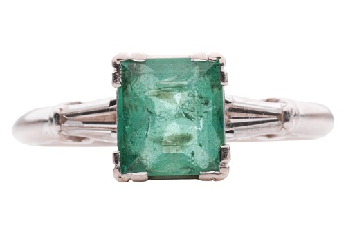 Lot 135 - An emerald and diamond trilogy ring; centred...