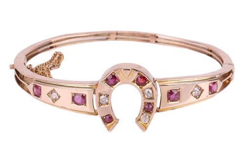 Lot 26 - A gem-set horseshoe hinged bangle, the central...