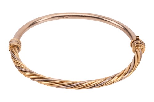 Lot 58 - A hinged bangle in 18ct bi-coloured gold, half...