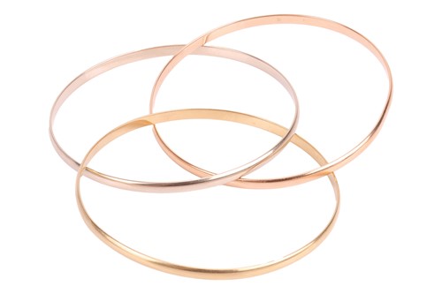 Lot 232 - Cartier – a trinity bangle in 18ct gold,...