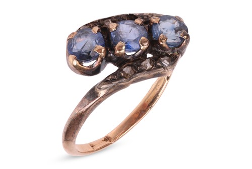 Lot 32 - A sapphire crossover ring, claw-set with three...