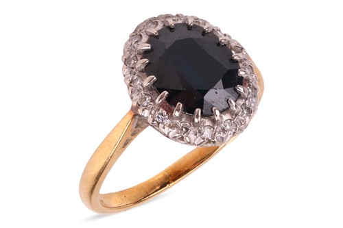 Lot 138 - A sapphire & diamond cluster ring, featuring a...