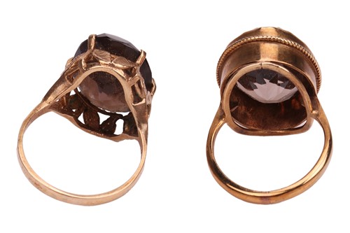 Lot 15 - Two smoky quartz rings; both set with oval-cut...