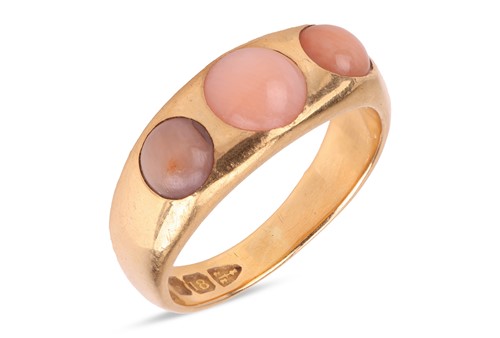Lot 29 - An angel’s skin coral three-stone ring in 18ct...