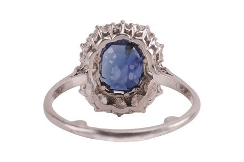 Lot 59 - A sapphire and diamond cluster ring, centred...