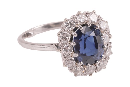 Lot 59 - A sapphire and diamond cluster ring, centred...