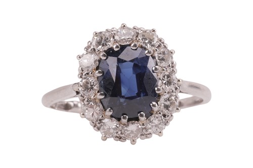 Lot 59 - A sapphire and diamond cluster ring, centred...