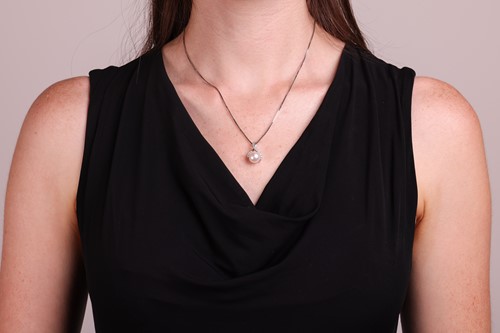 Lot 130 - A pearl and diamond pendant and chain, the...