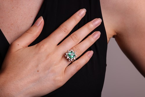 Lot 103 - An emerald & diamond cluster ring, the ring...