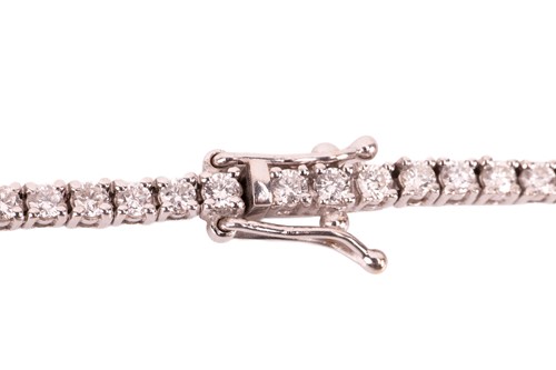Lot 104 - A diamond riviere necklace, featuring one...