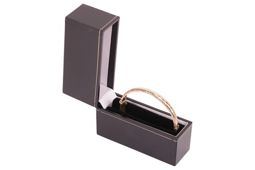 Lot A hinged bangle in 9ct gold, engraved to the...
