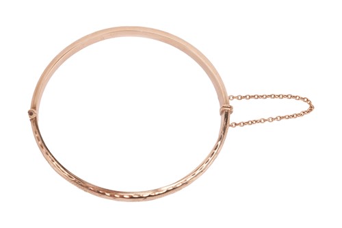 Lot A hinged bangle in 9ct gold, engraved to the...