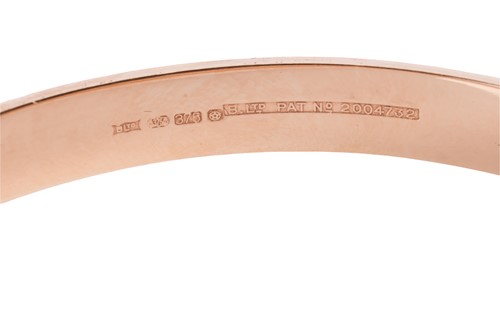 Lot A hinged bangle in 9ct gold, engraved to the...