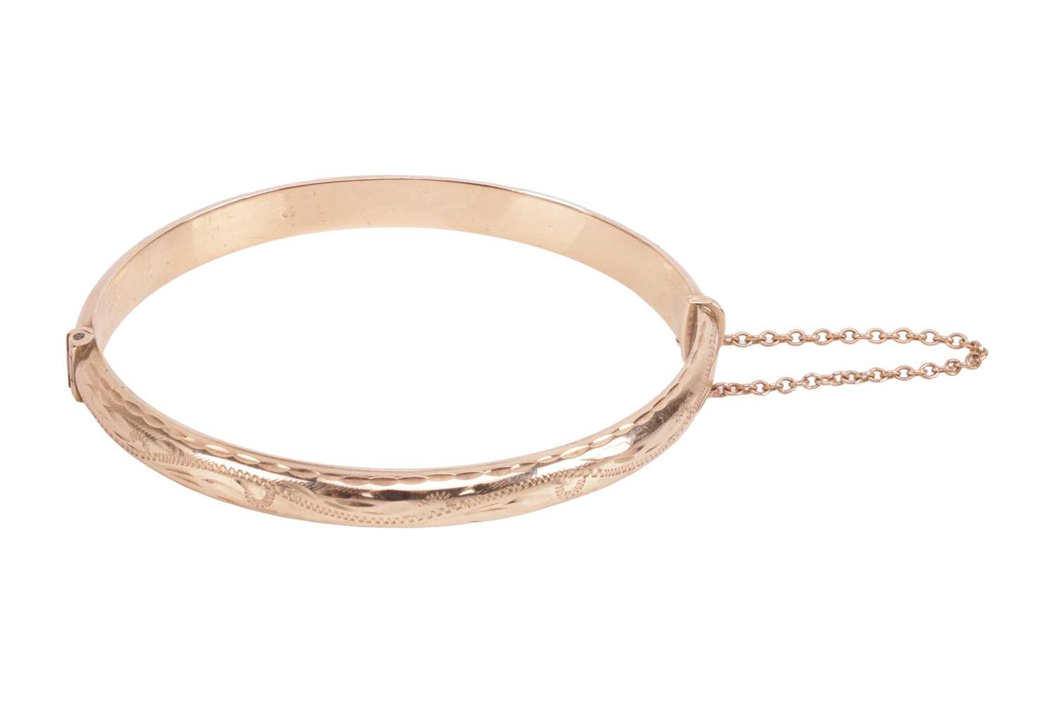 Lot A hinged bangle in 9ct gold, engraved to the...