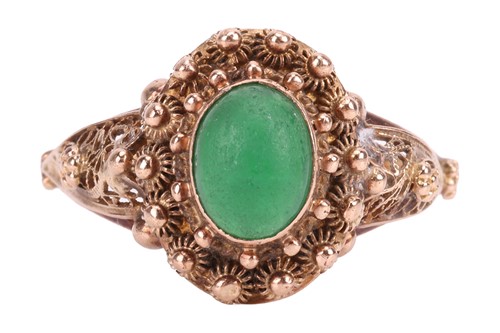 Lot A green paste ring, centrally-set with an oval...